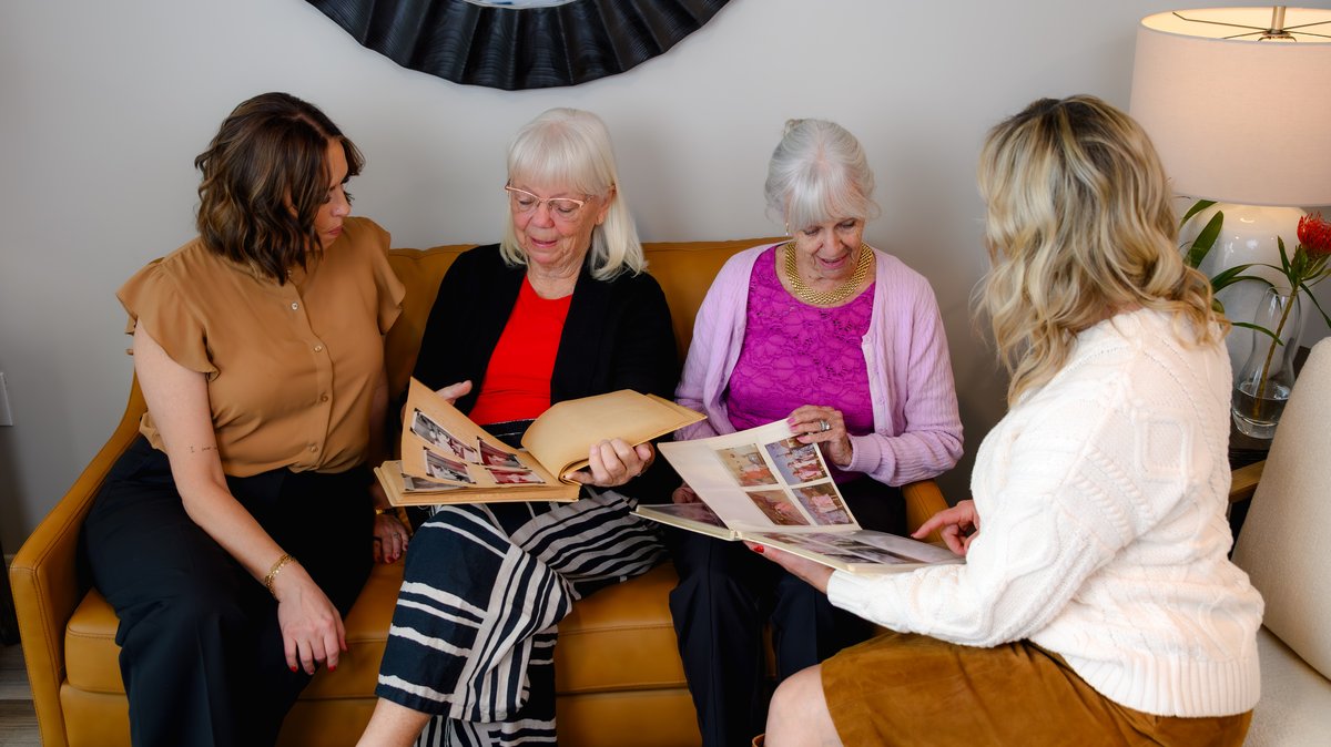 Two senior women looking through family photo albums with their New Day advisors
