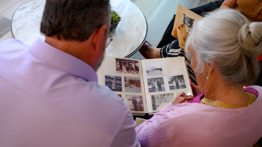 A senior woman revisiting family photographs with a memory care advisor